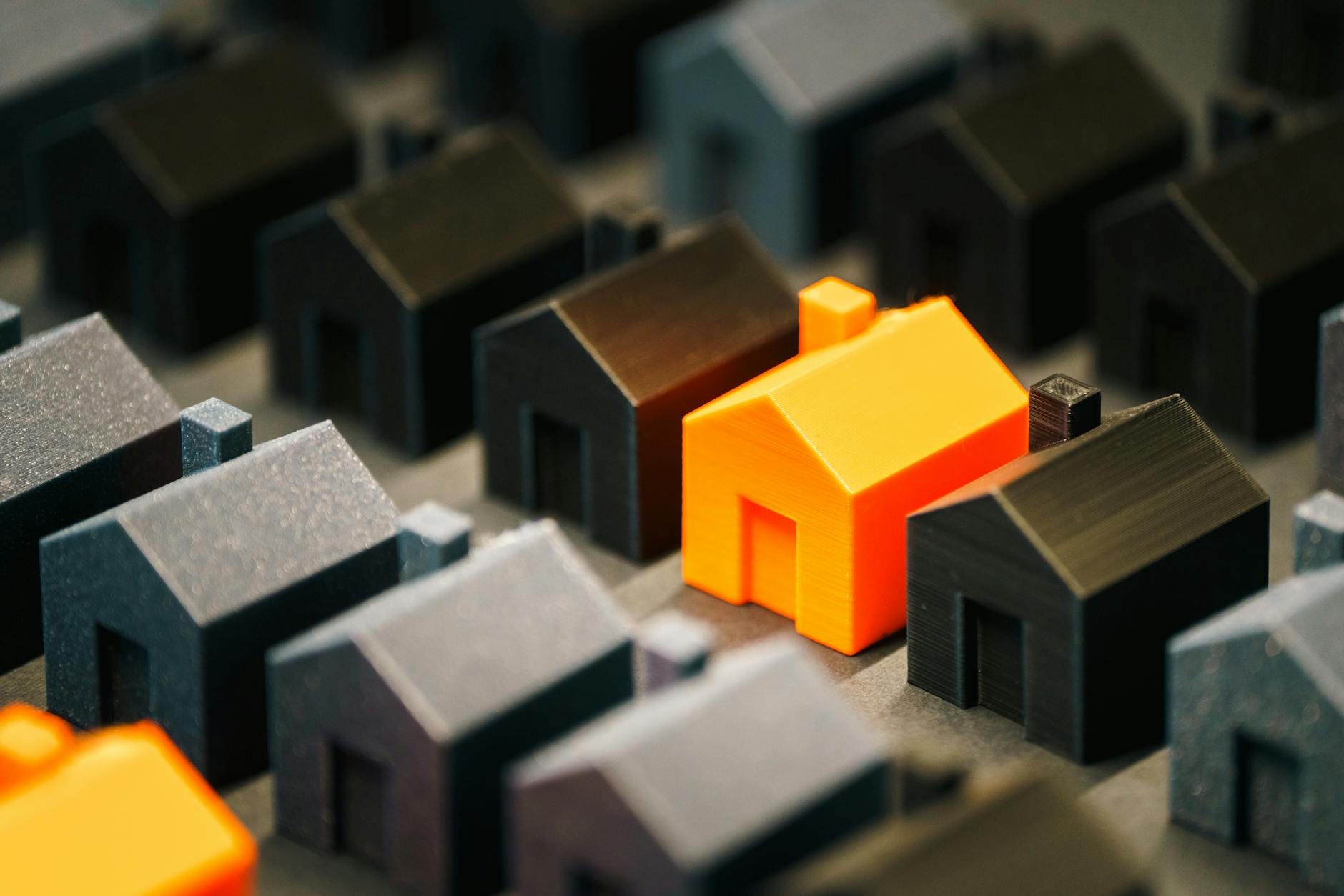 orange model house among black miniatures